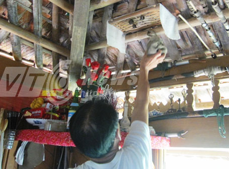 Thầy mo Lựng lấy túi phép trên bàn thờ xuống cho khách xem 